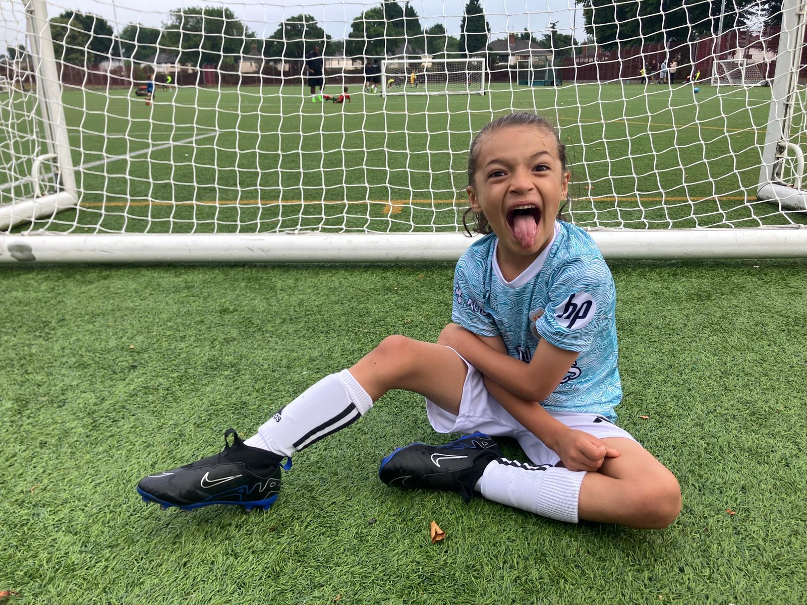 Xander sitting in front of the goal after a match, pulling a cheeky face
