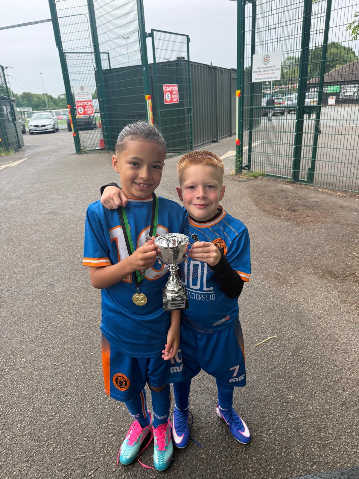 Xander and a team-mate holding a silver tournament winners cup