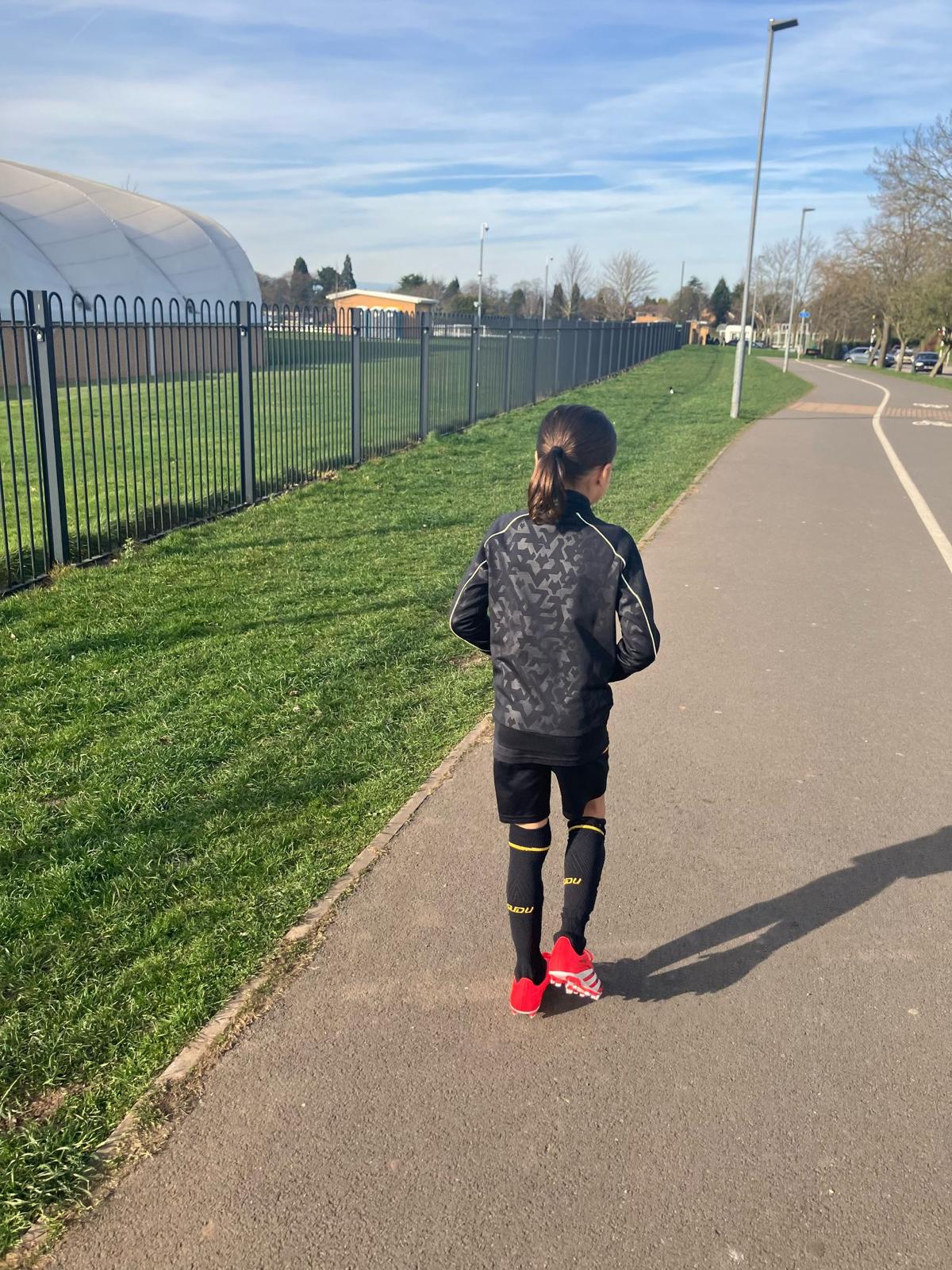 Xander walking towards the training dome in a black tracksuit and red boots