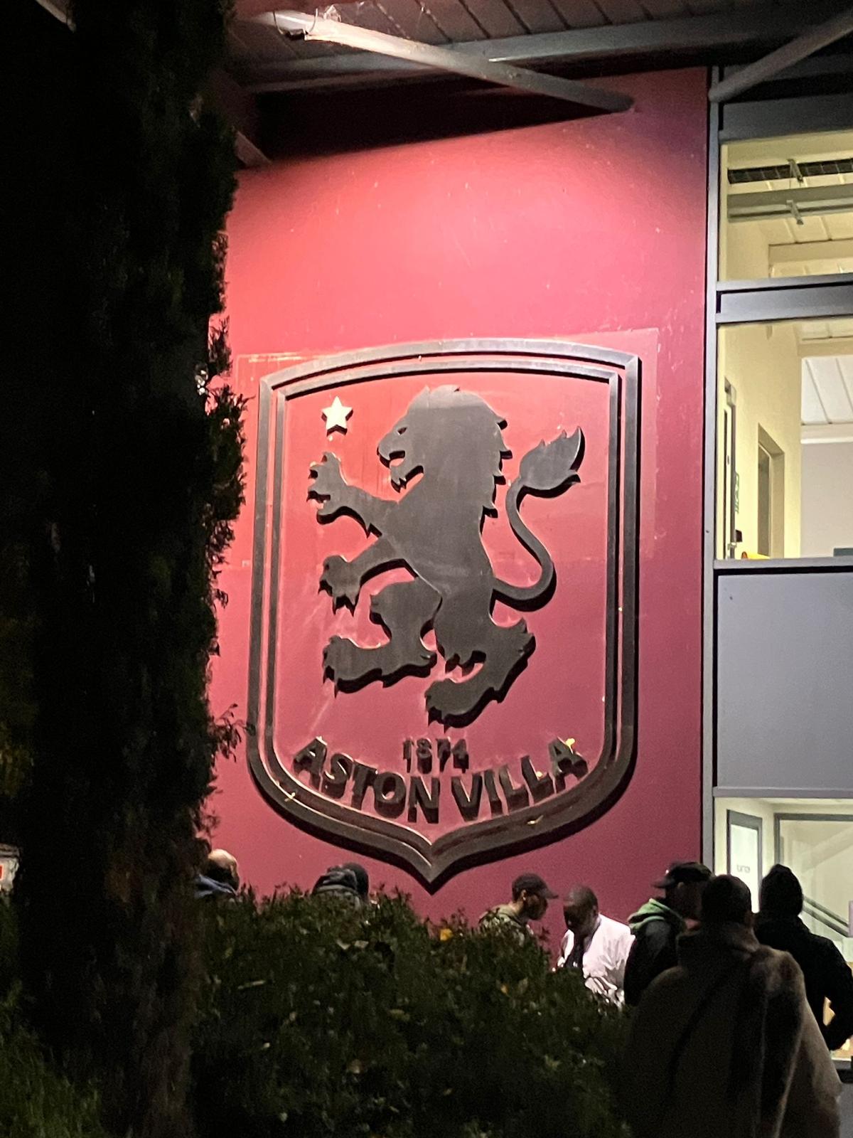 A club crest lit up on a stadium wall on a matchday evening