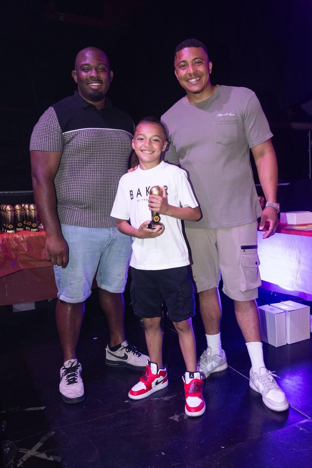 Xander receiving a trophy on stage between two coaches