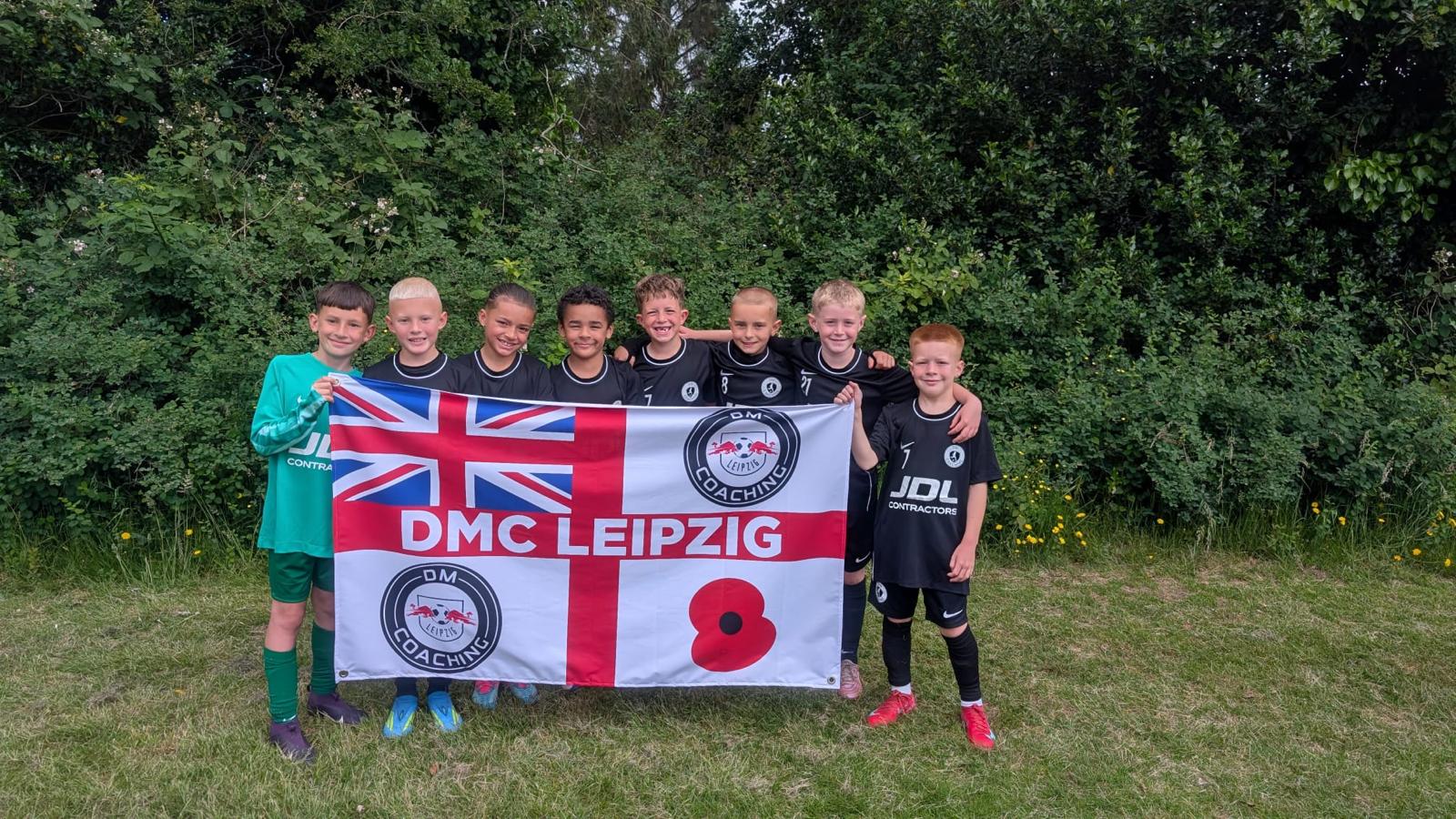 Xander's squad holding the DMC Leipzig flag on a grass pitch