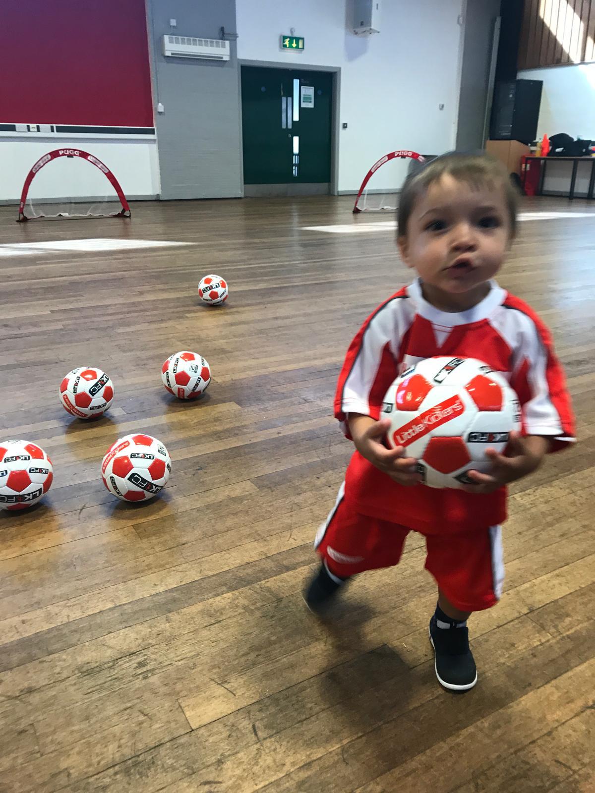 Xander as a toddler holding a football at his very first session