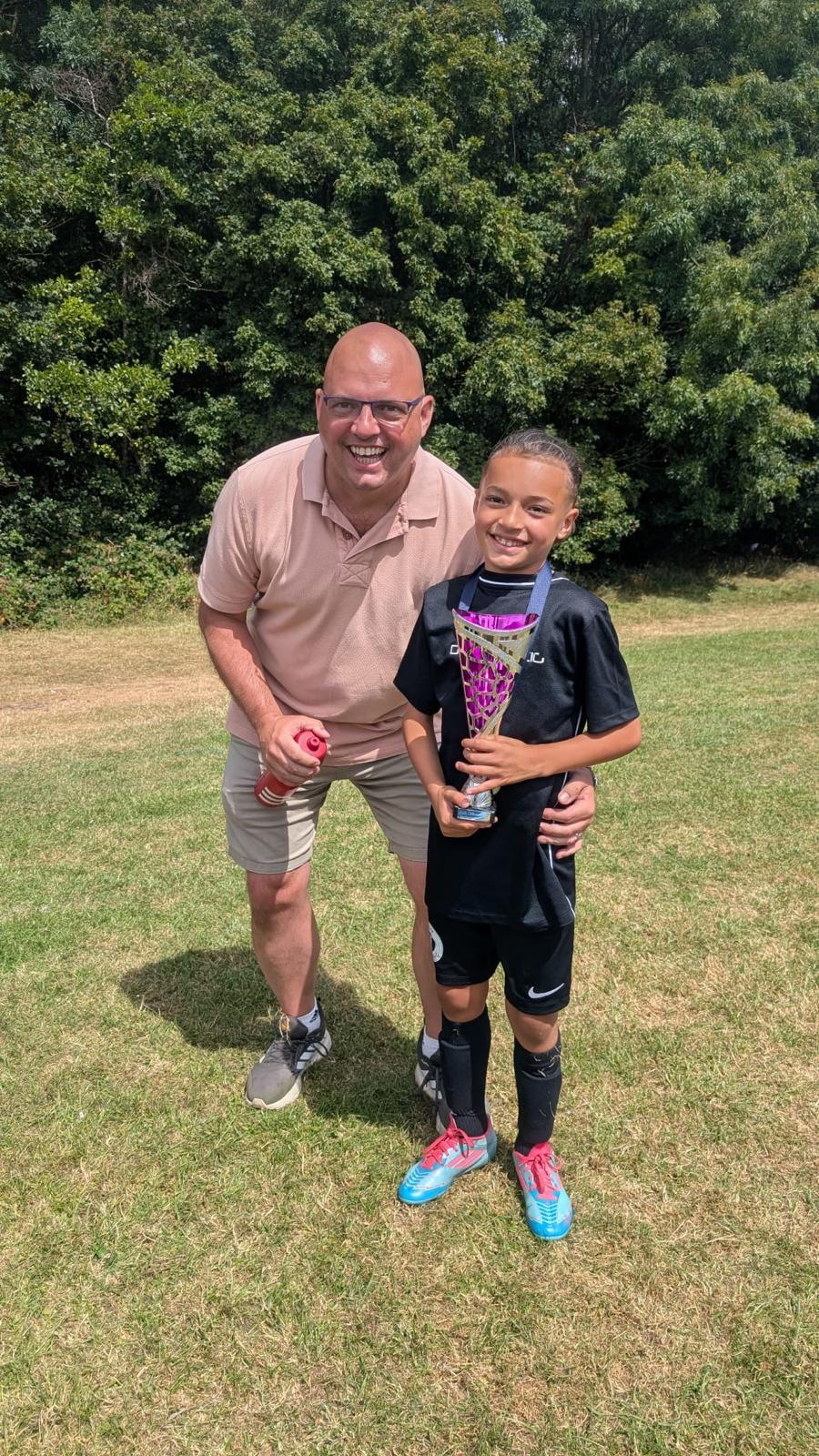 Xander holding a tournament trophy with his coach